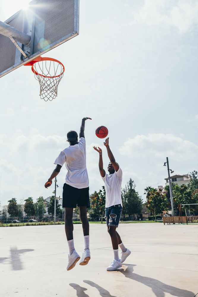 Black friends playing basketball in bright day