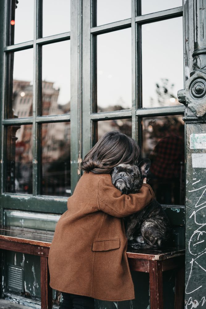 Girl hugging sad dog on city street