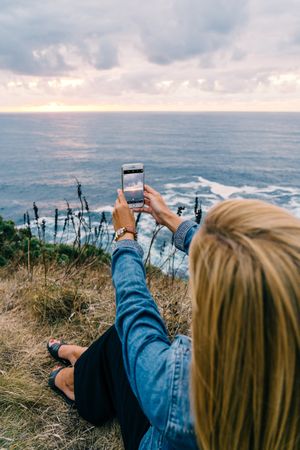 Female tourist taking shot of sea in twilight