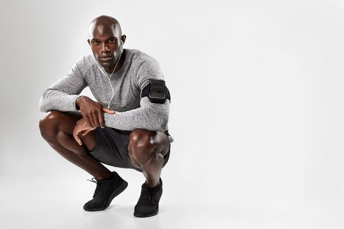 Fit young African man crouching over grey background