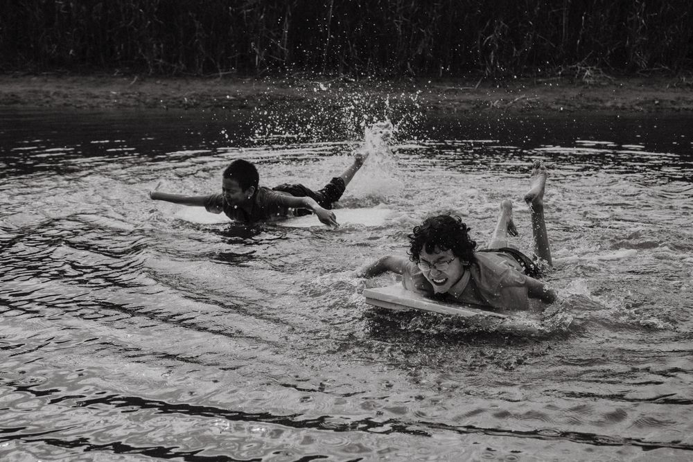 Happy boys swimming with board over water
