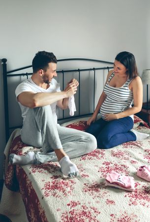 Man showing baby clothes to pregnant woman