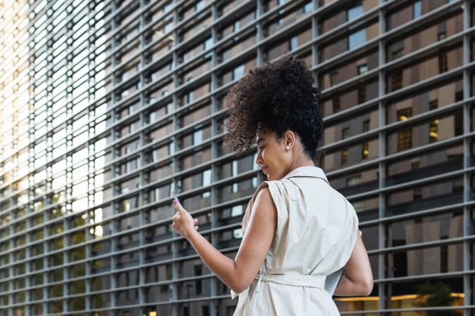 Black woman with laptop checking smartphone