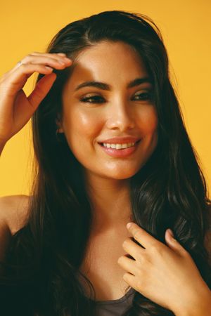 Smiling Hispanic woman looking away from camera in yellow room with her hand to her chest