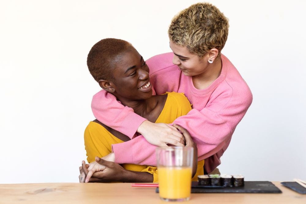 Loving female couple sharing sushi at home