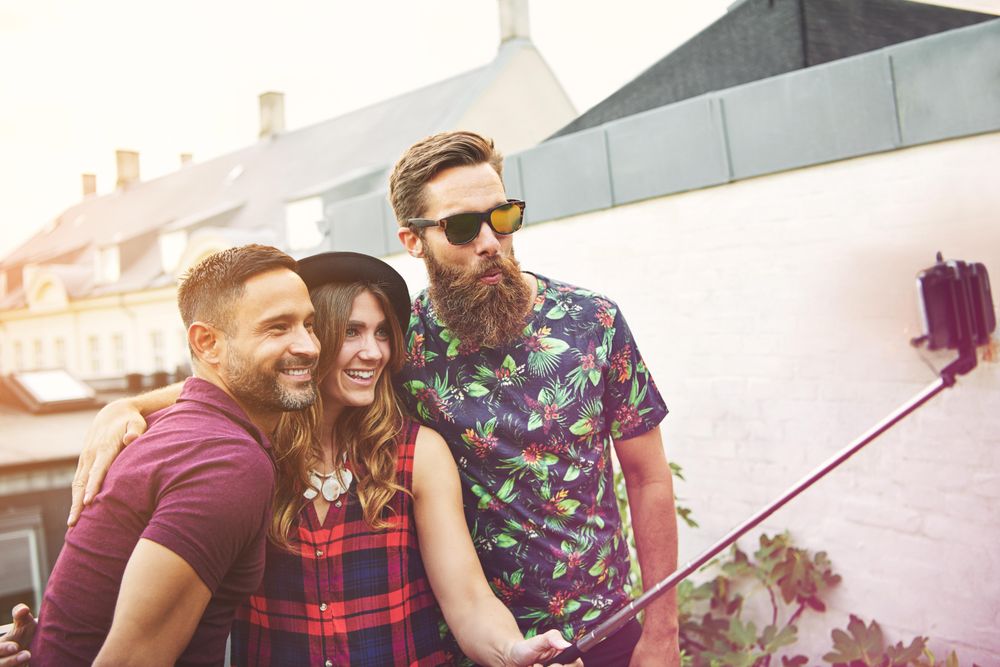 Three friends outside with a selfie stick