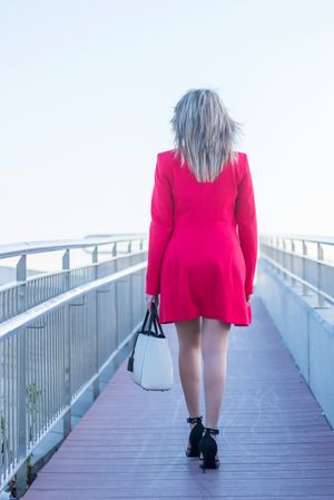 Back of woman in red coat walking on foot bridge