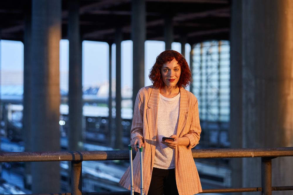 Smiling young woman holding phone at station