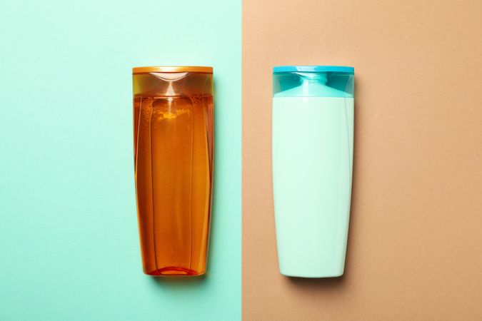 Blank bottles of shampoo on two tone background, space for text
