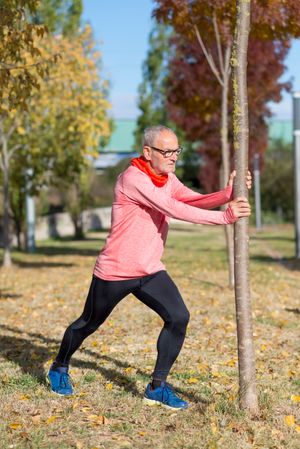 Man using tree for balance as he stretches legs