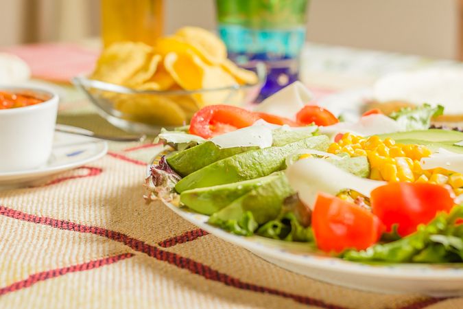 Traditional mexican food with a plate of fresh salad, nachos and a bowl of spicy sauce
