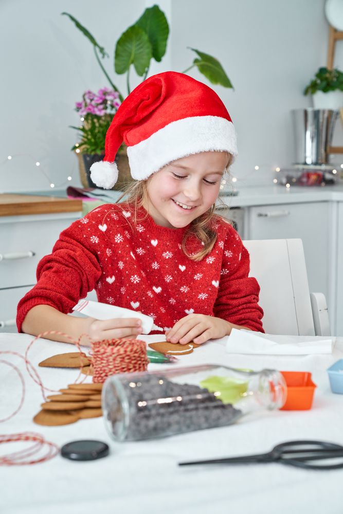 Smiling girl applying icing on gingerbread cookie