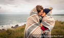 Couple kissing under blanket with choppy ocean in the background 5n8wlb