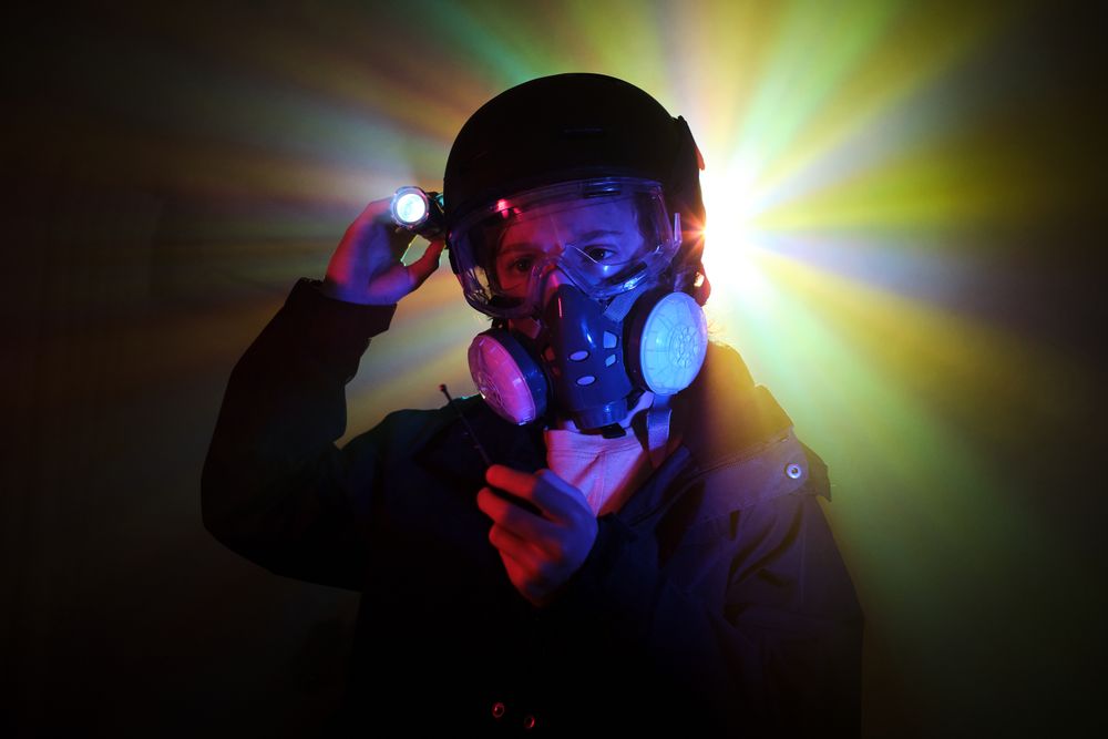 Thief in respirator with flashlight in darkness