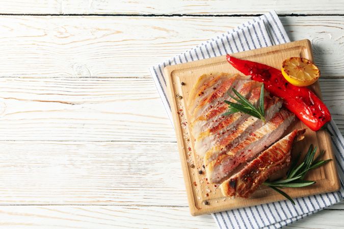 Board with fried steak on wooden background. Grilled food