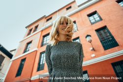 Looking up at smiling blonde woman standing by red building 5QDPn0
