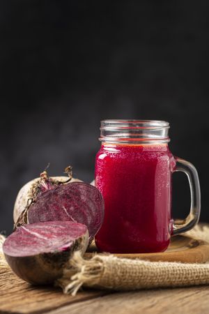 Red beet juice in a glass cup on the wooden table.