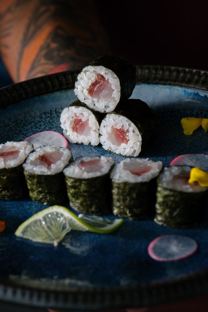 Anonymous waiter with delicious sushi rolls with salmon on tray