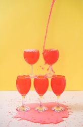 Rose liquid pouring and pilling into stacked wine glasses