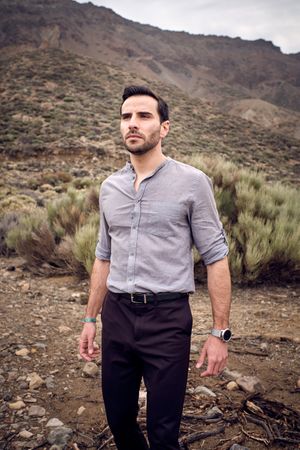 Confident young man standing on stony terrain with savanna grass