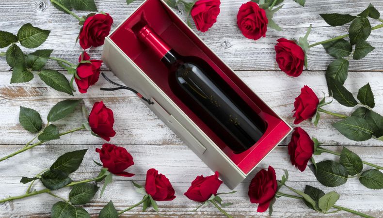 Happy Valentine’s Day celebration with red roses and wine on weathered wood