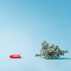 Santa's red sleigh pulling Christmas tree with bright blue background