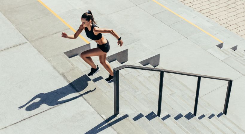 Female in sportswear exercising on staircase outdoors