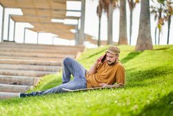 Relaxed man lying on the grass using the phone