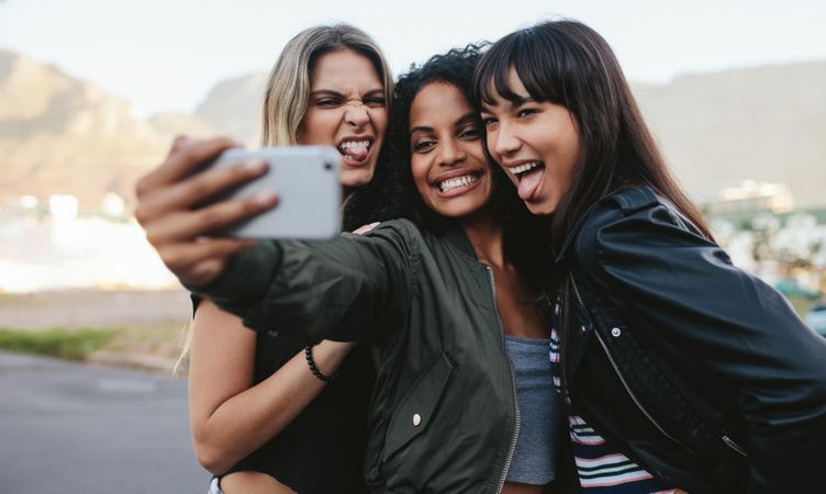 Group of female friends sticking tongues out posing for selfie