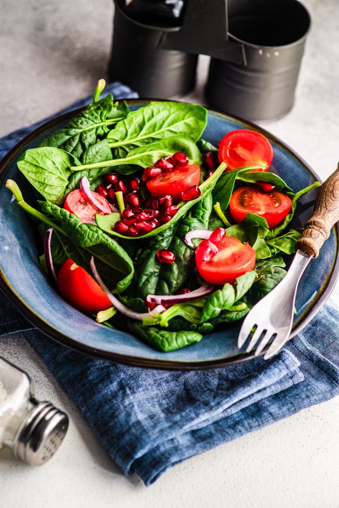 Fresh organic salad with spinach, tomato and pomegranate seeds