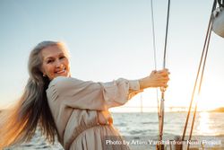 Older woman smiling and holding the lines of a sailboat 4dmWDb