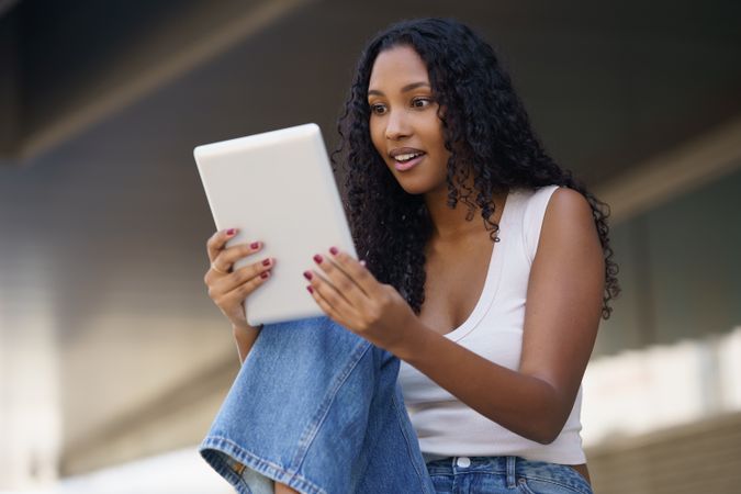 A Young Woman is Actively Engaged with Her Tablet While in a Casual, Relaxed Setting