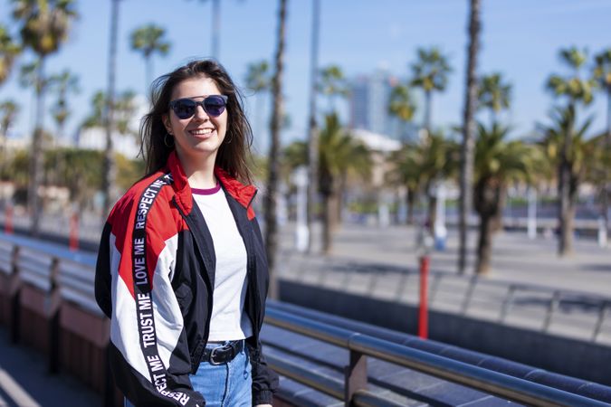 Smiling young woman in sunglasses looking at camera on sunny day