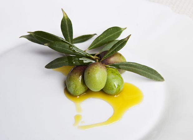 Green olives and leaves on plate