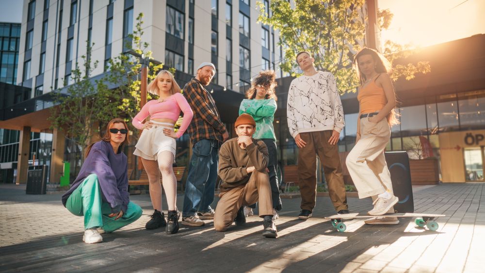 Vibrant Group Of Young Adults In Stylish Urban Wear Posing Confidently In A Sunlit Cityscape