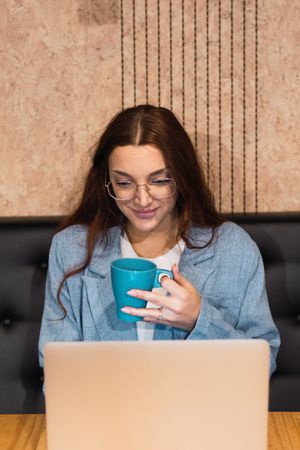 Female manager with coffee using laptop