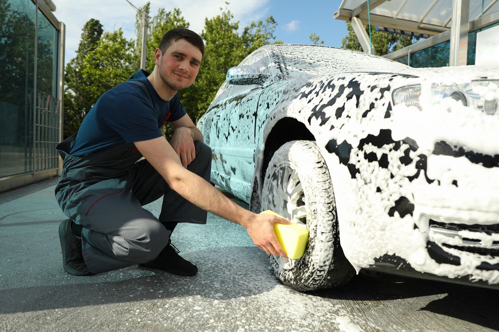 Man wipes the car with a sponge. Car wash. Clear car concept
