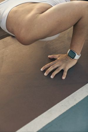 Close up of a woman's hands with a smartwatch in a plank position on a running track