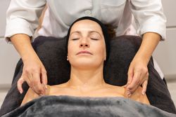 Female beautician massaging shoulders of client with stones