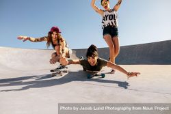 Group of women being silly while riding skateboards at skate park bGOyeb