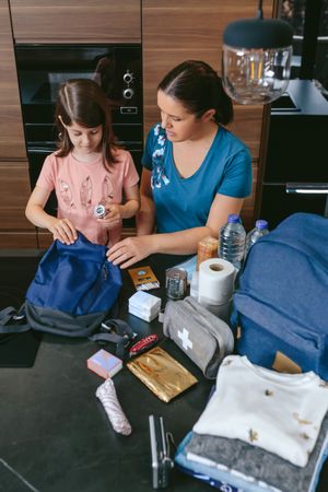 Mother preparing emergency backpack with her daughter