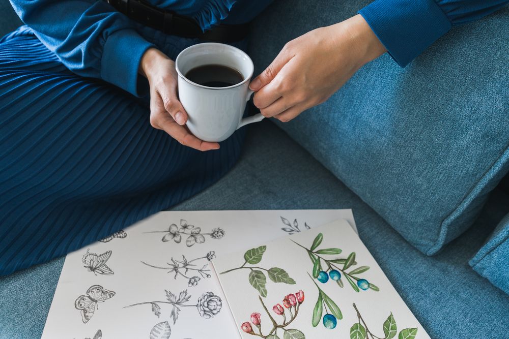 Young anonymous woman with coffee looking album with pictures
