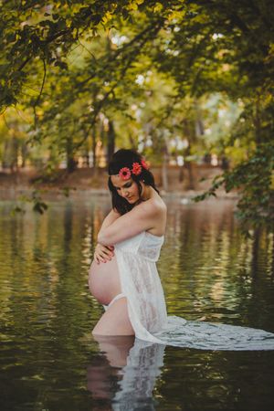 Pregnant woman standing in lake water