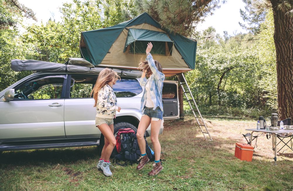 Women friends having fun in campsite into the forest