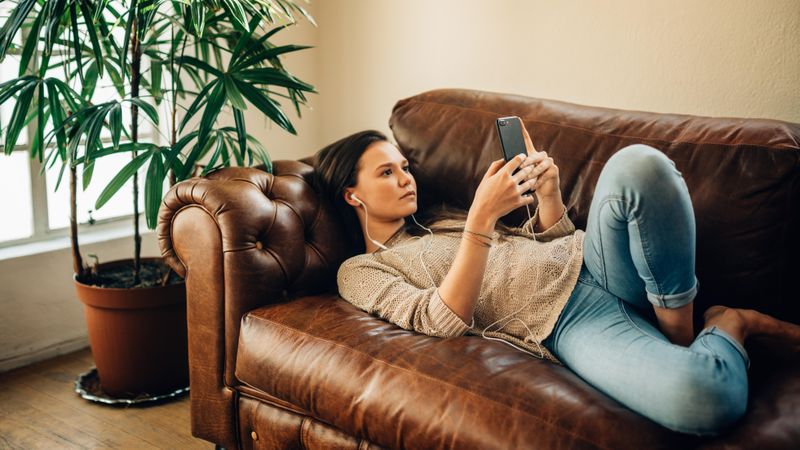 Woman relaxing at home and using her mobile phone