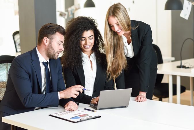 Co-workers brainstorming a project together in office around a laptop