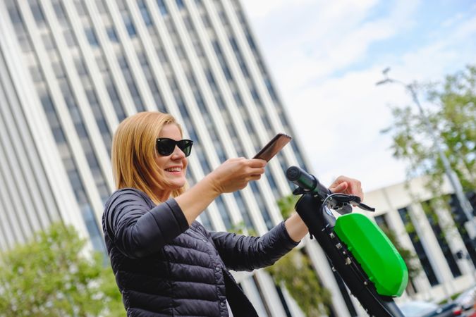 Woman browsing smartphone and riding electric scooter