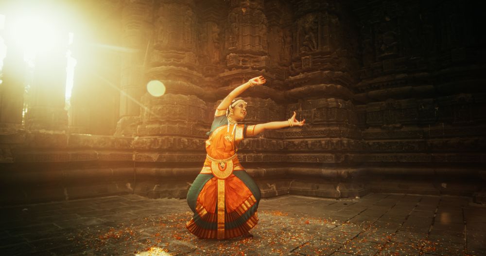 Dynamic Shot of Indian Woman in Traditional Clothes Dancing Bharatanatyam in Colourful Sari While Looking at the Camera.