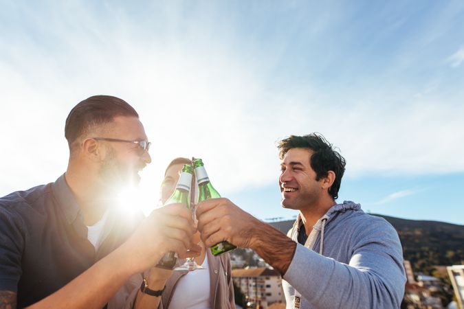Group of friends toasting beers at rooftop party