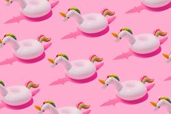 Inflatable unicorn pool toy pattern on pastel pink background